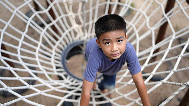 istock Young boy climbs rope structure at playground, showcasing determination and curiosity. image captures joy of childhood exploration and adventure in safe environment 2220157655
