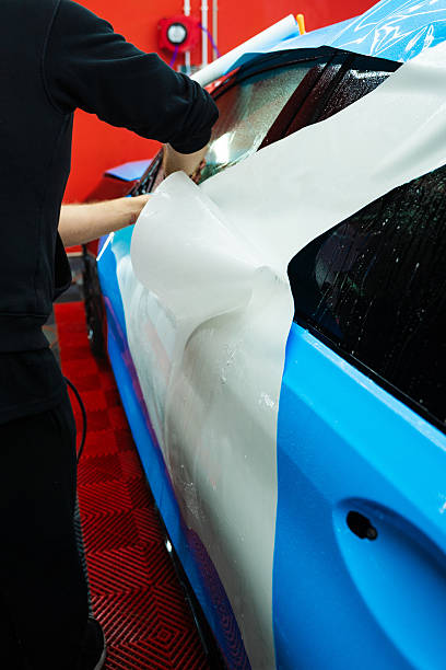 istock Wet PPF Wrapping on Car Panel in detailing center. Protective film layering during PPF wrap detailing to protect the car surface from scratches and UV. 2220160192