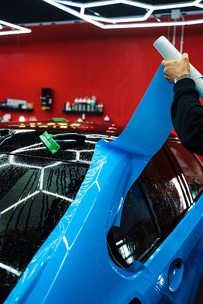 istock Protective film layering during PPF wrap detailing to protect the car surface from scratches and UV. Wet PPF Wrapping on Car Panel in detailing center. 2220160382