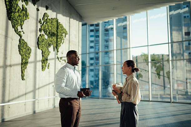 istock Businesspeople discussing strategy in modern office with green world map 2220160494