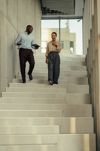 istock Businesspeople walking down stairs while having a conversation 2220160535