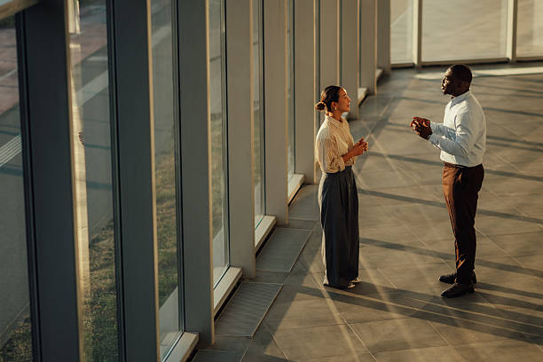 Businesspeople discussing near window in modern office building