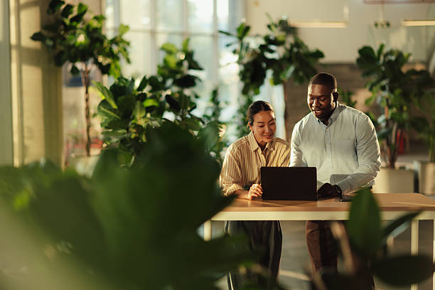 Business colleagues collaborating on laptop in green office space