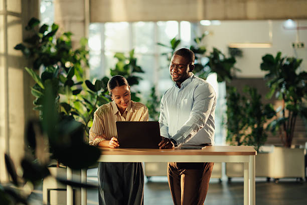 istock Diverse colleagues collaborating on laptop at standing desk in modern office 2220160592