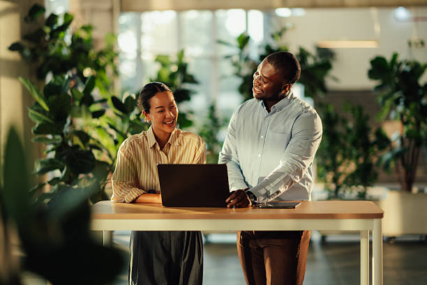 istock Smiling business colleagues collaborating on laptop in modern office 2220160595