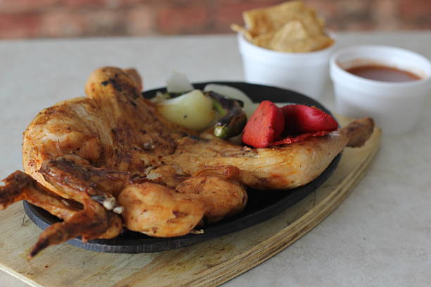 The image displays a tantalizing grilled chicken served on a sizzling plate with vibrant sides