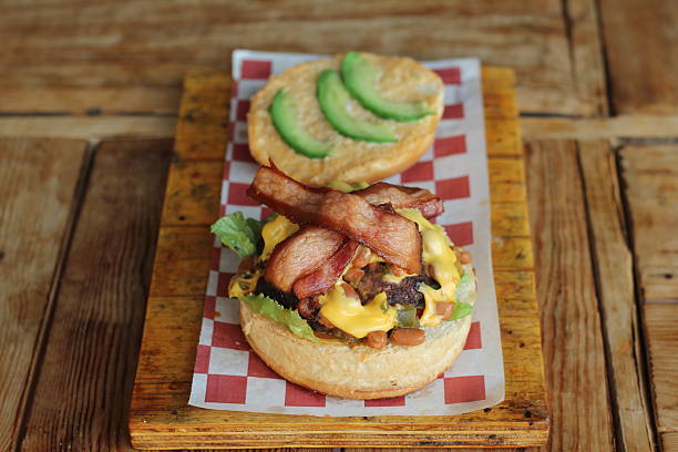 This close-up shot captures a gourmet bacon cheeseburger overflowing with flavor