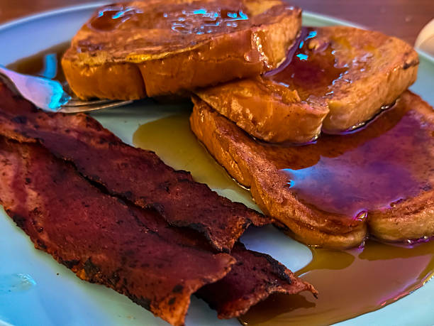 Close-up of a breakfast tray at Miami Airport featuring baked bacon, eggs, and coffee in a disposable cup.