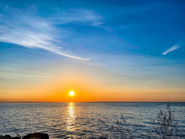 istock Golden Sunset Over Calm Ocean with Shimmering Reflection and Coastal View 2220164194