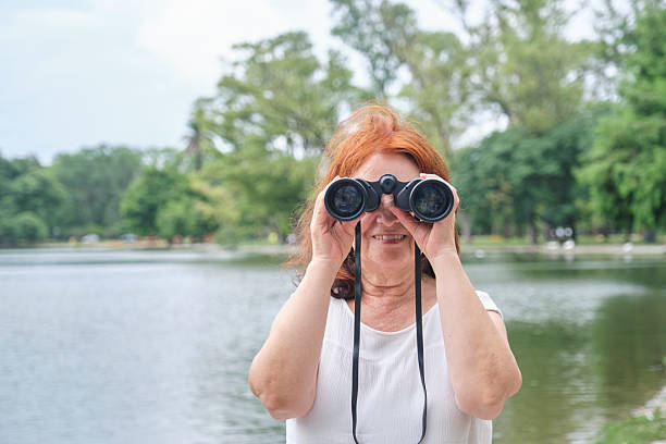 istock Senior Hispanic woman using binoculars smiling and looking at the camera. 2220167133