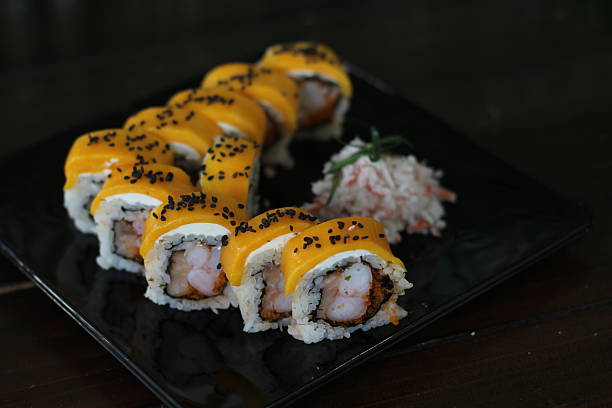 A beautifully arranged sushi platter featuring vibrant shrimp sushi rolls topped with creamy sauces, garnished with black sesame seeds for added texture and flavor.