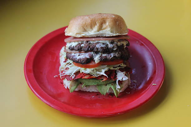 istock An oversized, layered burger packed with fresh ingredients like lettuce, tomato, and avocado, presenting a visually appealing and flavorful fast-food option for burger lovers. 2220167353