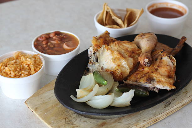 istock A tantalizing grilled chicken dinner on a sizzling plate accompanied by rice, charro beans, and crispy tortillas, evoking a cozy family meal experience full of comforting flavors. 2220167356