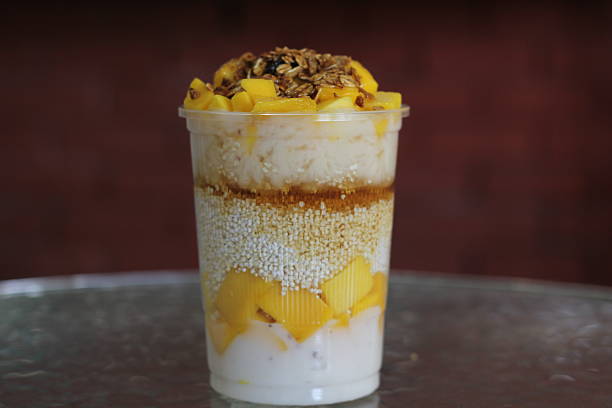 This enticing dessert features creamy layers of yogurt, rice, and fresh mango, topped with granola for a delightful sweet and crunchy finish, perfect for on-the-go enjoyment.