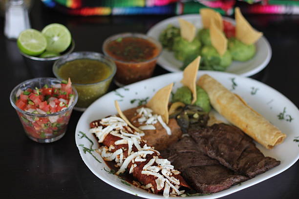 istock Showcasing a mix of authentic Mexican dishes, the platter includes grilled meat, enchiladas, salsa, and sides, representing a feast of traditional flavors and textures. 2220167754