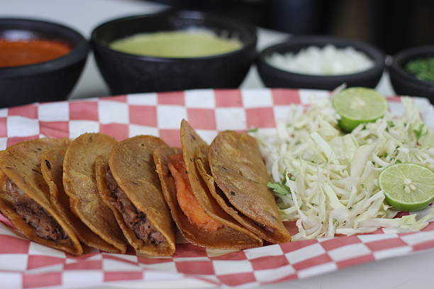 istock A platter of crispy tacos filled with savory pulled beef and topped with fresh cabbage, lime, and tangy salsa, celebrating the richness of Mexican street food. 2220167879
