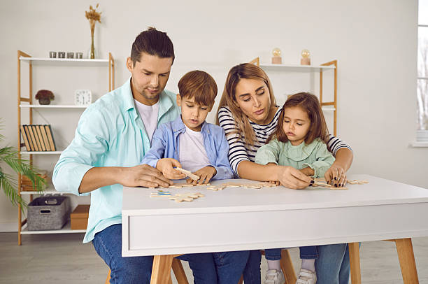 istock Parents and children sitting at a table, playing games and doing puzzles together 2220167891