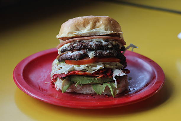 An indulgent, towering burger featuring multiple beef patties, fresh lettuce, tomato, and a rich layer of sauce, perfect for burger enthusiasts and fast food lovers.