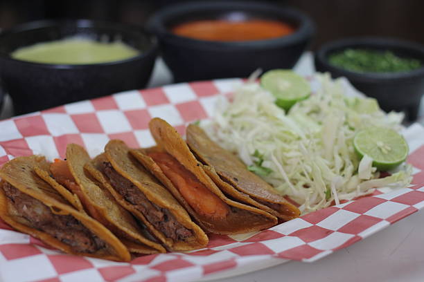 istock A delightful crispy taco platter showcases soft corn tortillas filled with savory beans and topped with fresh toppings, served with lime and salad, perfect for sharing or enjoying solo. 2220171728