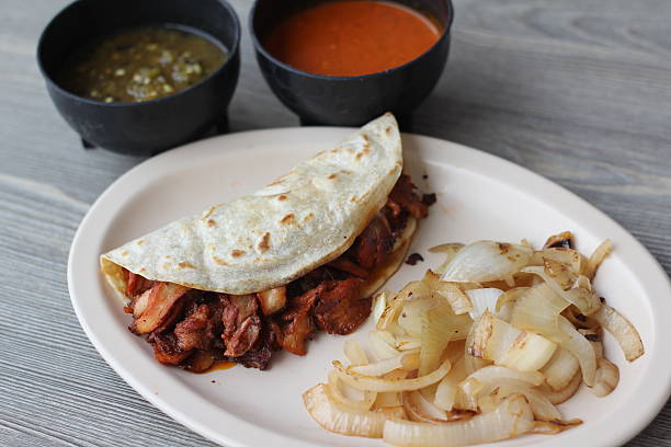 istock A delicious al pastor taco featuring grilled pork, accompanied by fresh salsas and grilled onions, offering a delightfully savory taste that represents authentic street food culture. 2220173428