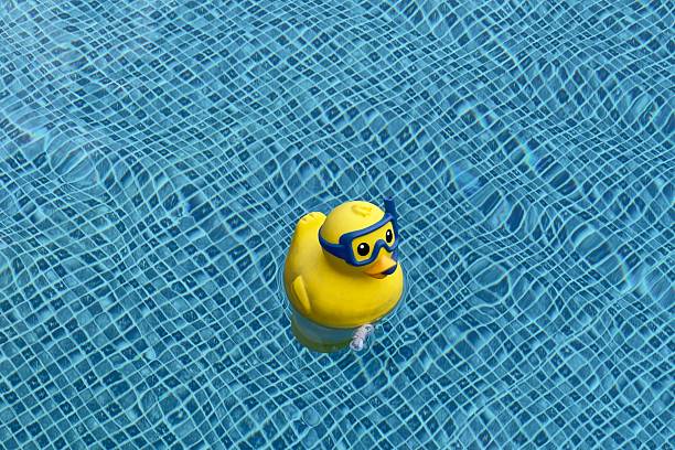 A yellow rubber toy floats in a blue pool with a mosaic pattern on the bottom.
