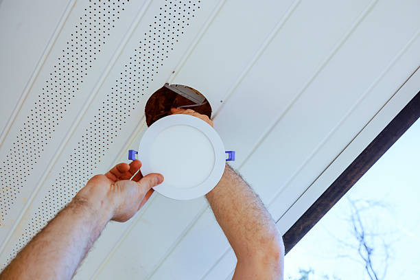 istock Man installs ceiling fixture in home during daylight hours in a modern living space 2220188604