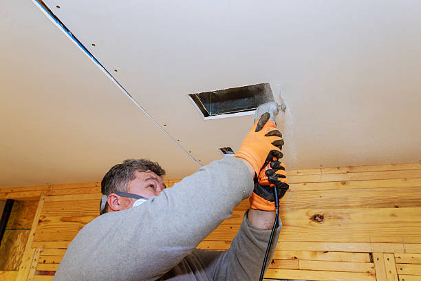 istock Worker installing ventilation duct in ceiling of wooden cabin during renovation 2220188612