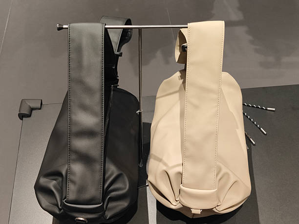 istock Black and beige leather backpacks on display, both in neutral tones with one being black and the other cream 2220190581