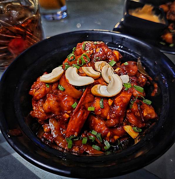 Stir Fried Chicken with Cashew Nuts, Close-up of cashew chicken stir-fry with bell peppers, dry chili, onions, and crispy chicken pieces on white background, Thai food