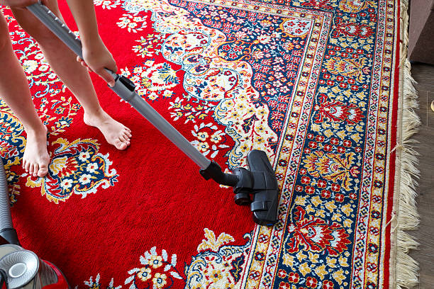 istock On a carpet with a colorful pattern, predominantly red and blue, human feet are visible as someone vacuums. This demonstrates everyday housework and care for cleanliness. 2220198682