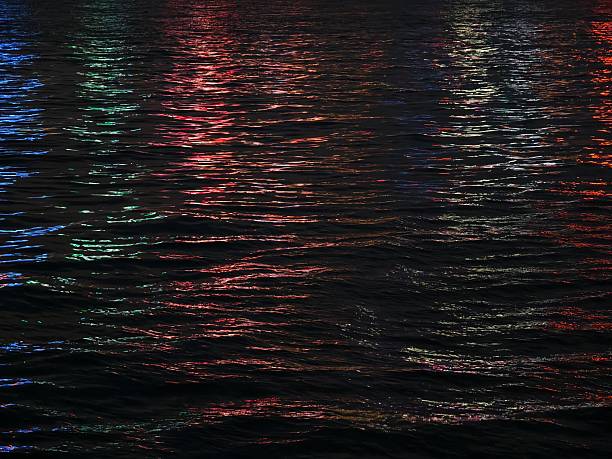 The colorful city lights create beautiful reflections in the water at night.