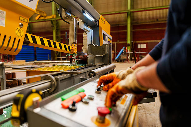 A man operates a CNC machine which engraves metal while working in a manufacturing and fabrication facility.