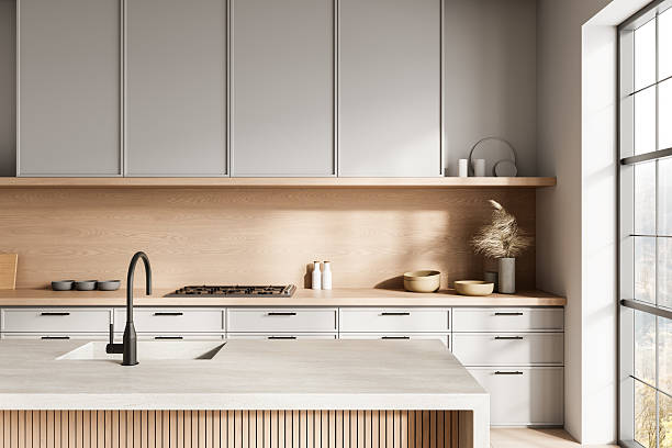 istock Modern minimalist kitchen interior with light wood and soft gray tones, large island, and natural light through big windows. 3D Rendering 2220206475