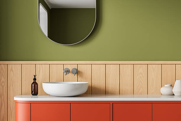 istock Modern bathroom interior with round mirror, olive green wall, wood paneling, red vanity cabinet, and countertop decor in minimalist style. 3D Rendering 2220206710