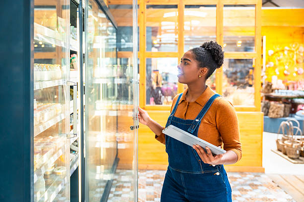 istock Supermarket employee checking products in refrigerator with tablet 2220209385