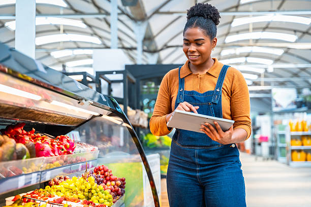 istock Smiling saleswoman using digital tablet checking fresh fruit in supermarket 2220209389