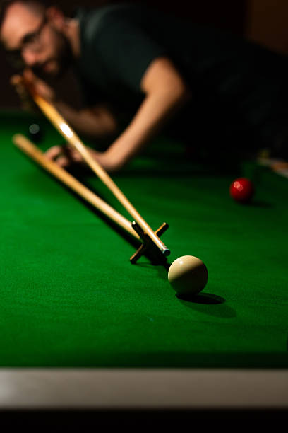 istock Player aiming white ball on snooker table with cue stick and rest 2220209649