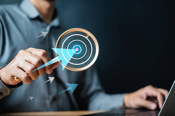 istock Target objective success goal dart. Bullseye growth aim. Strategy performance. A person is holding a magnifying glass and directing their attention towards a target with arrows. 2220214831