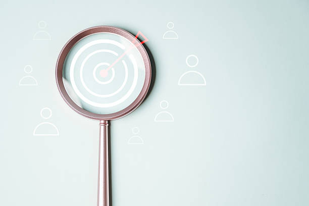 istock customer engagement target. target audience market. audience customer. A magnifying glass with a red dot in the center and a group of people around it. The people are arranged in a circle. 2220214869
