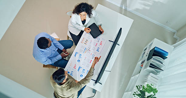 istock Top view group of business professionals meeting reviewing global data analytics presented on a large screen, discussing strategy and growth at the office. Finance meeting concept. 2220215561