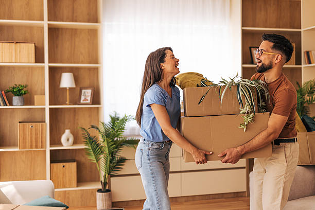 istock Happy couple carrying boxes and plants into new home 2220218769