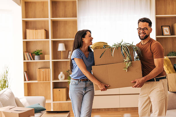 istock Happy couple carrying boxes and plants into new home 2220218789