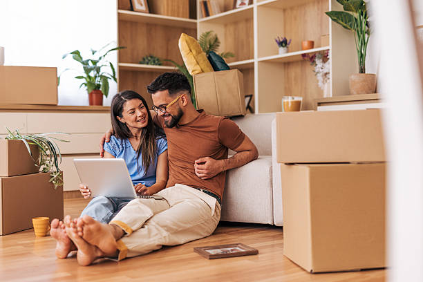 istock Couple using laptop while taking a break from moving into new home 2220219108