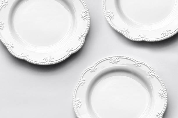 A cluster of decorative white ceramic plates with embossed edging, arranged in an overlapping top-down composition on a seamless white surface to showcase the set’s cohesive design and texture.