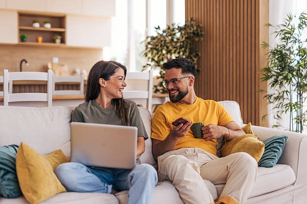 Young couple relaxing on sofa, working and enjoying a cup of coffee