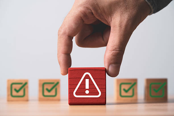 istock Hand holding triangle caution warning sign in front of correct sign mark for notification error and maintenance concept. 2220220649