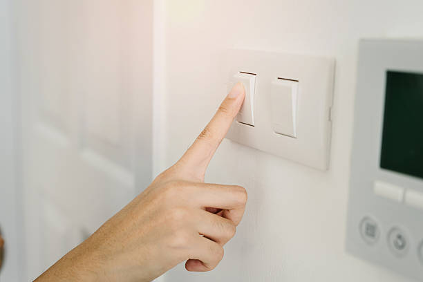 istock Hand pressing light switch to control lighting in modern interior space for energy conservation and ambiance adjustment 2220226035
