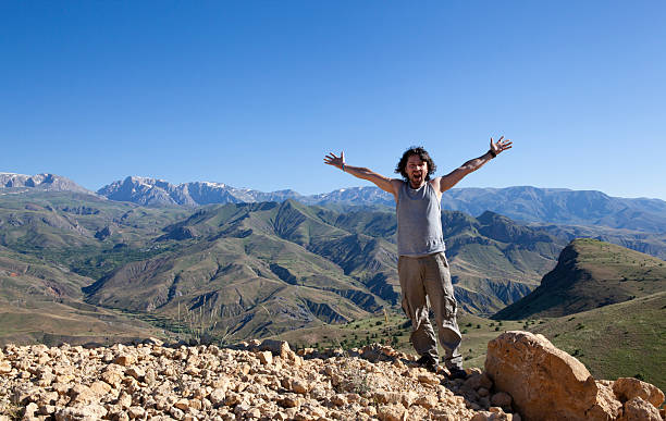 istock Young man with open arms in the mountains 2220227710