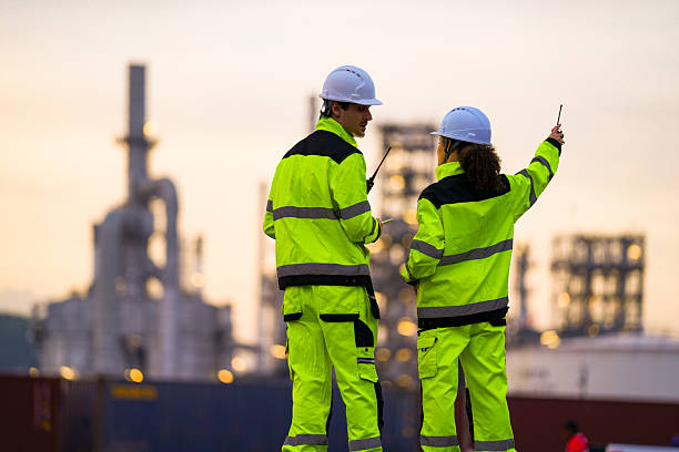 istock Two safety engineers in high-visibility suits inspect a tablet at a refinery site during sunset. Industrial plant towers rise in the background, creating a contrast with the warm sky. 2220232622