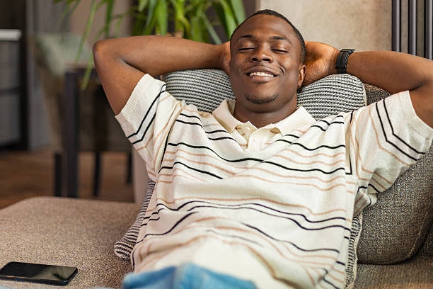 istock Attractive young african man relaxing on a couch at home 2220232755